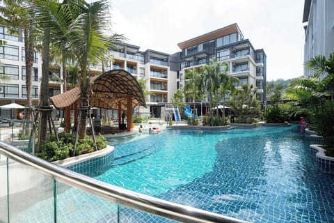 Spacious tropical pool area with sun loungers, parasols, and lush greenery for ultimate relaxation.