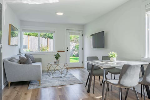 The living room offers a cozy space to relax, complete with a TV and fresh white walls throughout for a clean, airy vibe