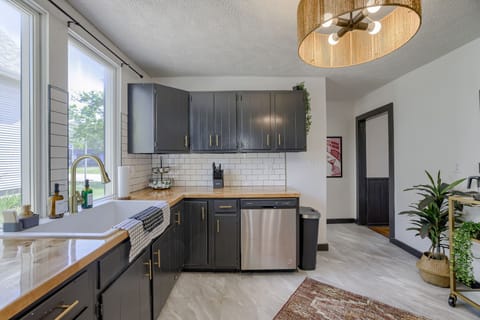 Bright kitchen with black cabinets, wood counters, and stainless appliances.
