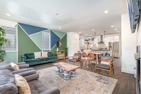 Welcoming living area with a vibrant green accent wall, large Smart TV, fireplace, and plush seating arranged to take in the serene outside views. (1st Floor)