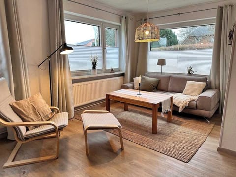 Gemütliches Wohnzimmer mit Decken, Kissen, Sessel und Leselampe.
