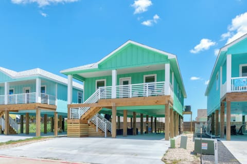Bright coastal homes on stilts with covered parking create a cheerful beachside community under sunny skies.