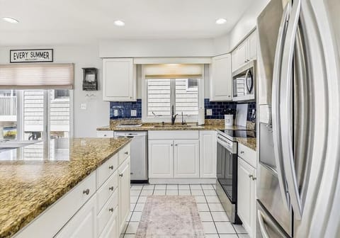 Bright and airy kitchen featuring stainless steel appliances, ample storage, and a stylish coastal design.