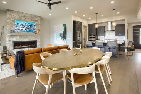 Open dining area with stylish table and seating, stone fireplace, and modern mountain ambiance.