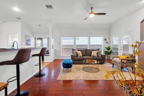 Bright and spacious open floor plan living room with a modern kitchen. Features a large kitchen island with seating, perfect for casual dining or gathering with friends and family.

