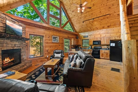 Vaulted ceilings, a stone fireplace, and natural light streaming through forest-facing windows—this open-concept living space is the heart of the cabin.