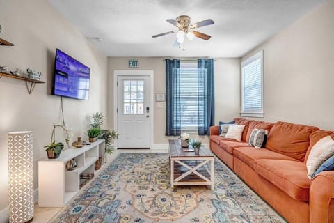 - Bright and inviting living room with cozy sectional, mounted TV, and pops of greenery
- Warm tones and layered textures create a space perfect for movie nights or reading
- Close to the front entry and filled with natural light from tall windows