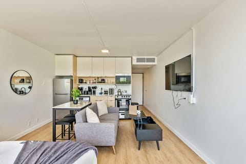 Bright living area w/ cozy seating, wall-mounted TV & open layout flowing into the kitchen