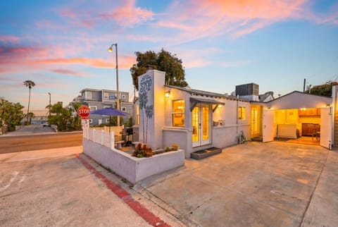 The SRP cottage glowing at sunset, warm interior lighting spilling out through the French doors onto the patio.