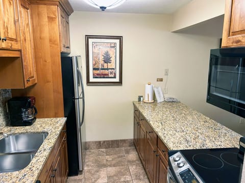 A well-appointed kitchen showcases sleek black and stainless-steel appliances, ample storage, and a cozy dining nook, ideal for family meals in a mountain resort setting.