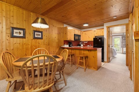 Cozy kitchen with wood-paneled walls, dining table, and essential appliances.