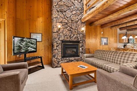 Cozy living room with stone fireplace, plush seating, and rustic charm.