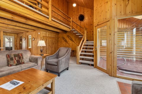 Charming log cabin living room with comfy seating and rustic wood walls.