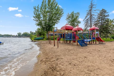 Sandy beach with a colorful playground set right by the water.