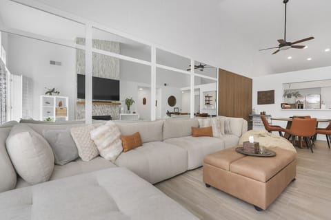 Living room equipped with 72` TV, fireplace, comfy couch, and ottoman that folds out into a twin bed