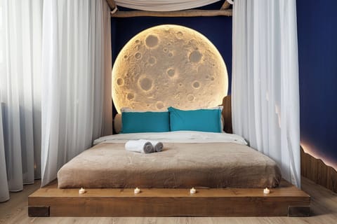 Four-poster queen bed framed by flowing curtains and a radiant moon headboard, creating a romantic and celestial sleeping atmosphere.