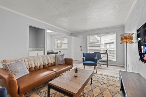 A bright and stylish space with a sleek leather sleeper sofa and 4K smart TV.