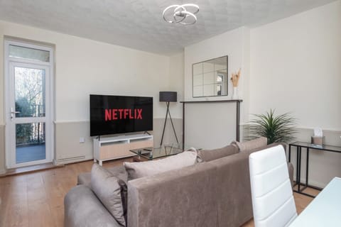 Stylish living room with plush sofa-bed, coffee table, 65” TV, balcony view.