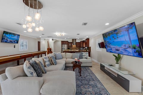 This inviting living space blends modern design with cozy comfort, featuring a plush sectional sofa, two large wall-mounted TVs, and a sleek entertainment console.