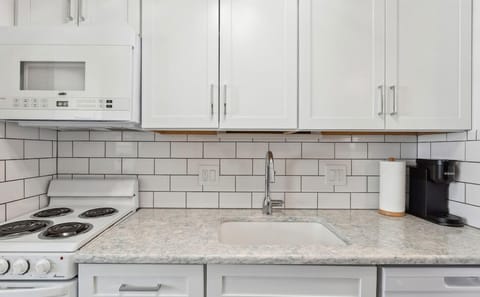 Well-equipped kitchen with stovetop, fridge, microwave, and Keurig