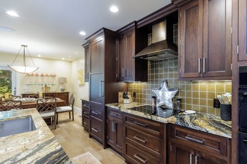 This beautifully appointed kitchen blends warmth and function with rich custom cabinetry, granite countertops, and ample prep space.