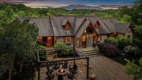 Rustic lodge with stunning mountain views, cozy fire pit, and twinkling lights—perfect for relaxing in nature.