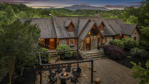 Rustic lodge with stunning mountain views, cozy fire pit, and twinkling lights—perfect for relaxing in nature.