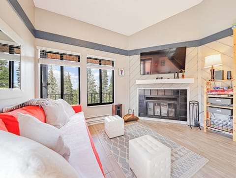 Living room area with sleeper sofa, large windows with views to the trees and 48" smart TV