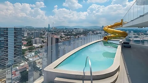 Sky-high shared pool deck w/ sweeping city views & a vibrant waterslide for a refreshing dip above the skyline