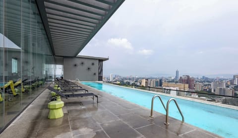 Shared rooftop infinity pool & deck w/ loungers, perfect for a refreshing swim while enjoying sweeping city views