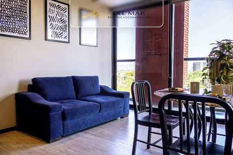Cozy living room w/ blue sofa & dining table by the window, filled w/ warm natural light