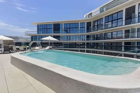 Shared sun-soaked pool beside the modern building, perfect for cooling off & relaxing under the open sky