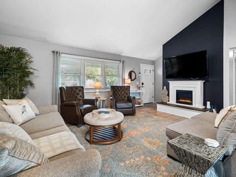 Inviting living room with fireplace and mounted TV 🔥📺. Plush seating and natural light from large windows create a perfect spot to relax. The open layout flows effortlessly from entryway to lounge 🛋️.