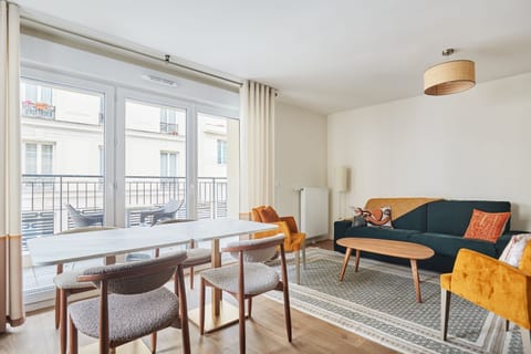 Spacious and sunlit living room with modern seating and large windows—perfect for relaxing after a day in Paris.