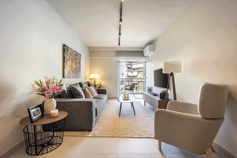 Stylish lounge with vibrant art, natural light, and balcony access for relaxing Athens evenings.