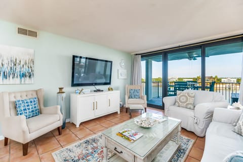 Coastal-inspired living area with flat-screen TV and sliding glass doors to covered balcony overlooking Old River Orange Beach