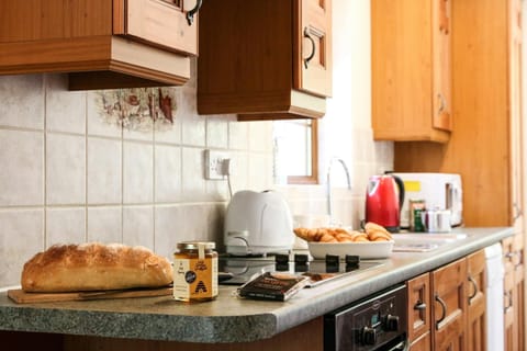 Kitchen with cooker, microwave, toaster, kettle, sink, bread and honey