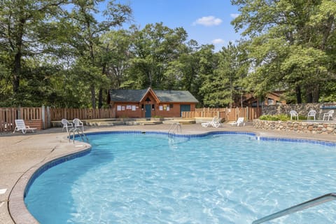 Refreshing outdoor pool surrounded by lush greenery and a cozy cabin.