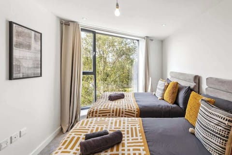 - Spacious bedroom with twin beds dressed in cozy gray and gold bedding  
- Floor to ceiling windows offer serene tree views and natural light  
- Comfortable setup perfect for families or group travelers seeking rest  
