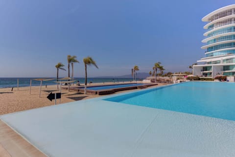 Shared oceanfront infinity pool overlooking the sandy beach & swaying palms
