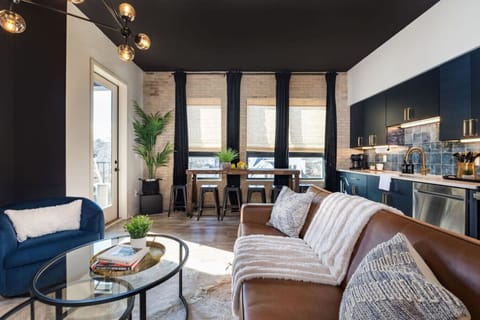 Dark, sophisticated living space with navy blue accents and an open kitchen.