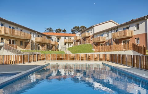 Dive into relaxation at the shared heated pool, nestled amid charming architecture and lush greenery, inviting you to unwind after a day at the beach.