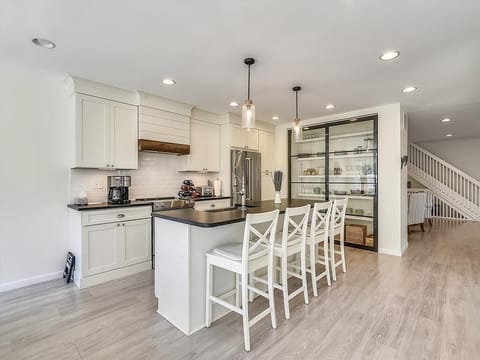 The modern kitchen is a chef’s delight, featuring sleek cabinetry, a spacious island, and high-end appliances, including a Keurig, perfect for serving up breakfast before heading out to the beach.