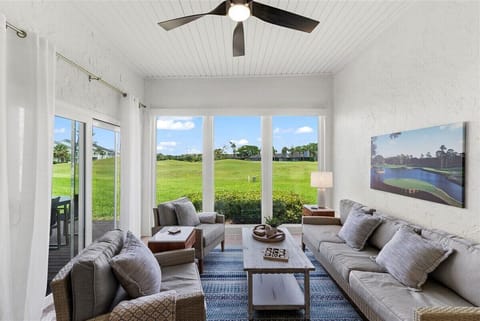 Relax in the sun-drenched living room with high ceilings, natural light, and sweeping views of the golf course