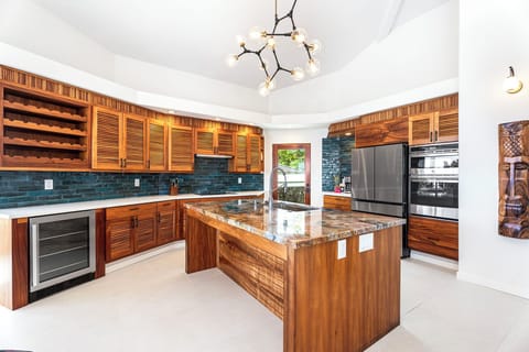 Chef’s kitchen with custom wood cabinetry and stainless steel appliances, offering generous prep space and bar seating for casual entertaining.