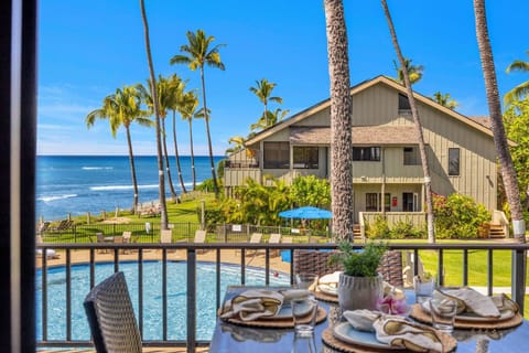 Along the walkway, palms and chairs edge the shoreline, the building rising just behind.