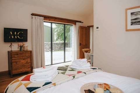 Bedroom with double bed, solid oak furniture, flat-screen TV and a patterned wardrobe.