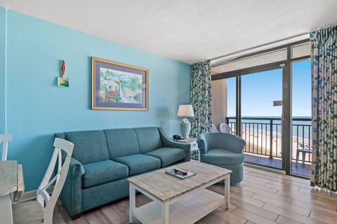 Oceanfront living room with cozy seating, queen sofa sleeper, and private balcony overlooking the Atlantic at Beach Cove Resort.