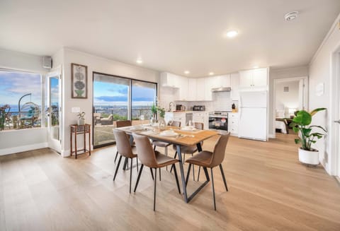 A bright and airy living space featuring a cozy dining area, a sleek kitchen with pretty accents—perfect for enjoying meals with a view. Large windows bring in plenty of natural light!
