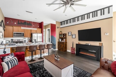 Immerse yourself in Music City vibes with this stylish open-concept living space. Features include a full kitchen, cozy fireplace, large TV, and fun decor like a piano-themed trim and guitar accents—perfect for relaxing or entertaining!
